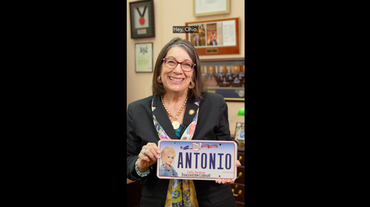 Senator Nickie Antonio holding a Dolly Parton License Imagination Library of Ohio license plate that reads Antonio
